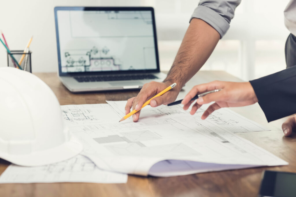 Architect or engineer team discussing a project design using blueprints and a laptop computer at the office before visiting home